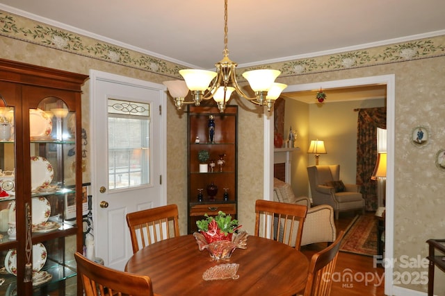 dining space with ornamental molding, hardwood / wood-style floors, and a notable chandelier