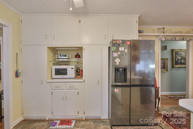 kitchen with white cabinetry, crown molding, stainless steel fridge, and ceiling fan