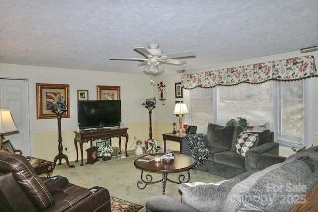 carpeted living room featuring ceiling fan, ornamental molding, and a textured ceiling