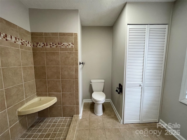 1404 Linwood Rd, Gastonia, NC 28052 - full bathroom featuring a closet, toilet, tile patterned floors, a tile shower, and a textured ceiling