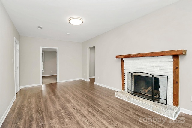 unfurnished living room with visible vents, baseboards, wood finished floors, and a fireplace