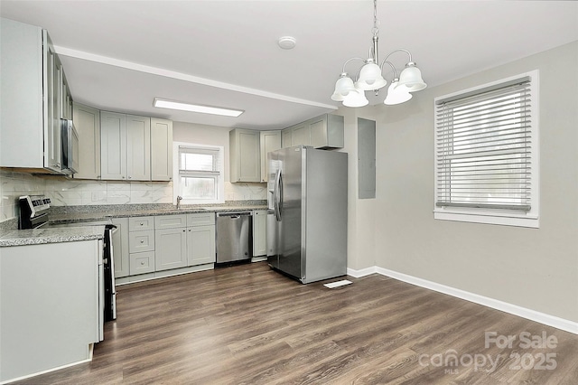 kitchen featuring baseboards, dark wood finished floors, appliances with stainless steel finishes, a notable chandelier, and tasteful backsplash