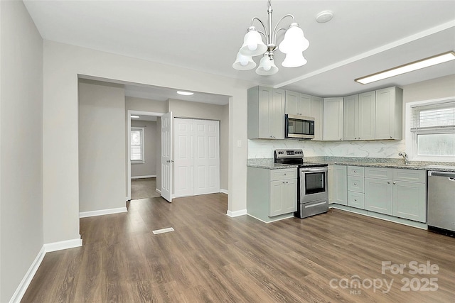 kitchen featuring backsplash, baseboards, light stone countertops, dark wood finished floors, and stainless steel appliances