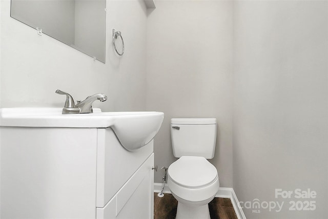 bathroom featuring toilet, vanity, baseboards, and wood finished floors