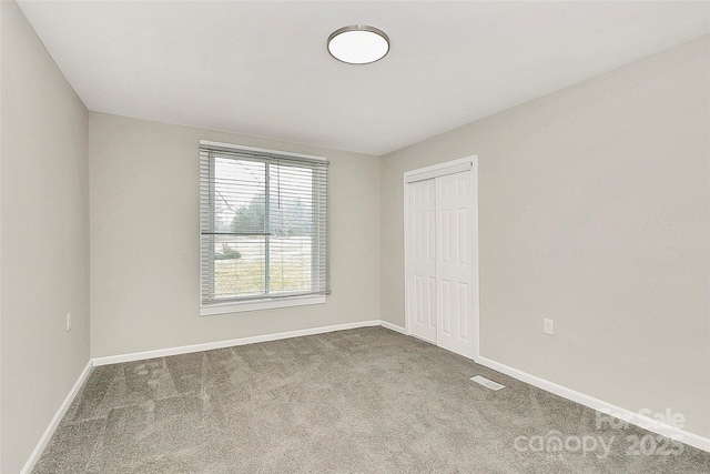 unfurnished bedroom featuring a closet, baseboards, carpet, and visible vents