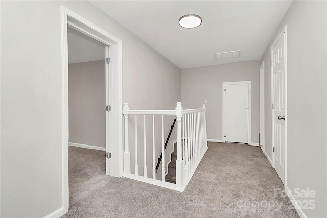 hall with visible vents, carpet flooring, an upstairs landing, and baseboards