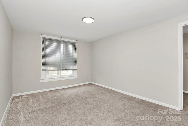 carpeted empty room featuring baseboards