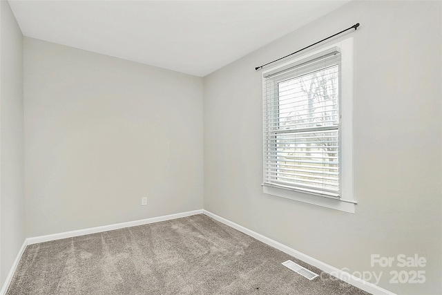 carpeted spare room featuring visible vents and baseboards