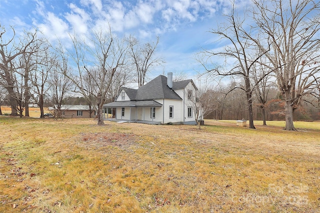 exterior space with a yard, roof with shingles, and a chimney