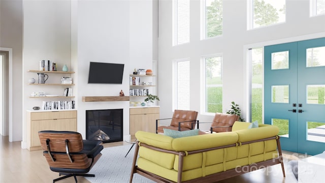 living room featuring french doors, light hardwood / wood-style flooring, and a high ceiling