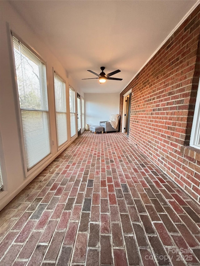 unfurnished sunroom with ceiling fan