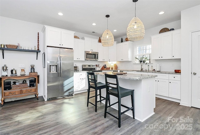 kitchen featuring a breakfast bar area, white cabinetry, decorative light fixtures, a center island, and appliances with stainless steel finishes