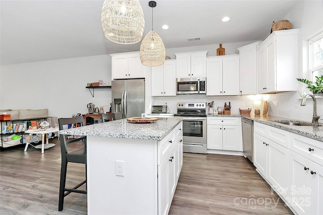 kitchen featuring a kitchen island, appliances with stainless steel finishes, sink, white cabinets, and hanging light fixtures