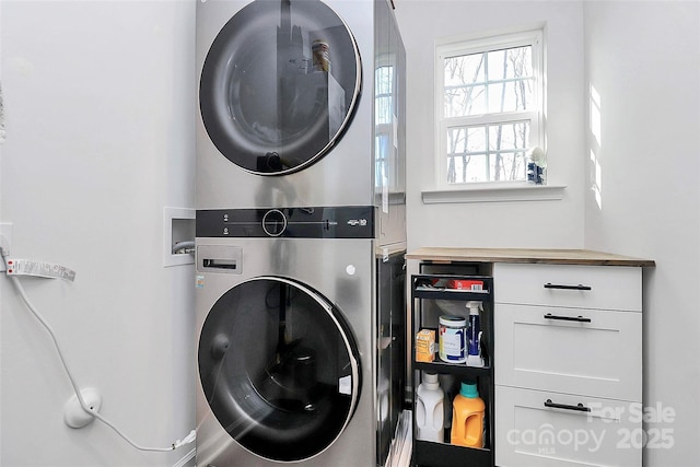 washroom featuring cabinets and stacked washer and clothes dryer