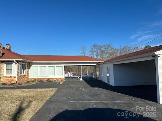 view of side of property with a garage, an outdoor structure, and a carport