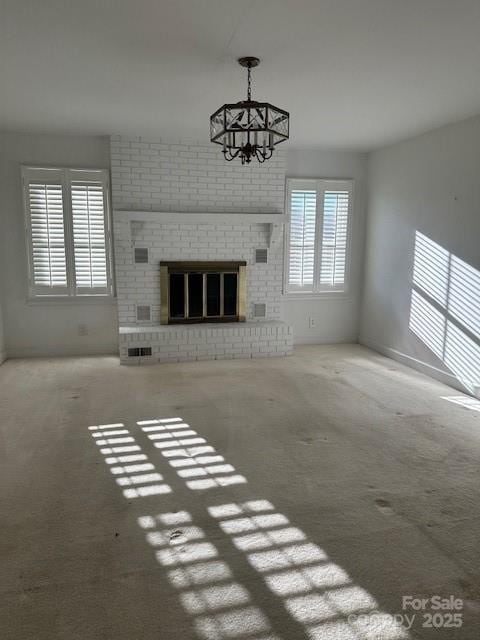 unfurnished living room featuring carpet flooring, a fireplace, and a chandelier