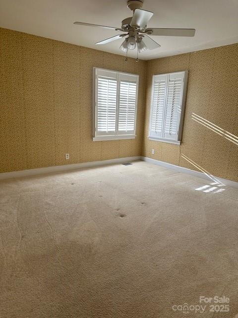 spare room with ceiling fan and carpet