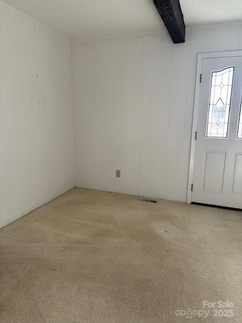 entryway with beamed ceiling, light carpet, and a textured ceiling