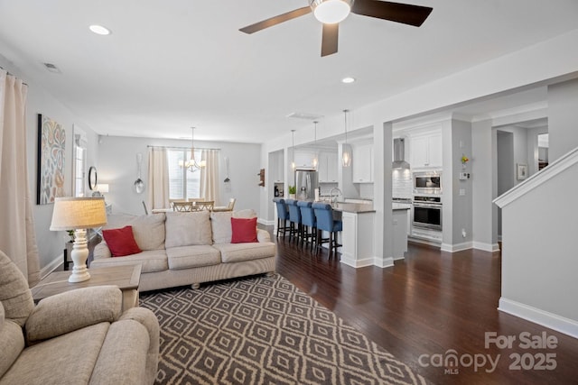 living room with dark wood-type flooring and ceiling fan with notable chandelier