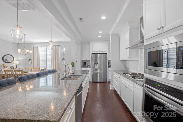 kitchen with a spacious island, sink, stainless steel appliances, light stone countertops, and white cabinets