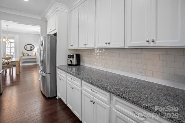 kitchen with dark hardwood / wood-style floors, stainless steel refrigerator, tasteful backsplash, white cabinetry, and dark stone counters