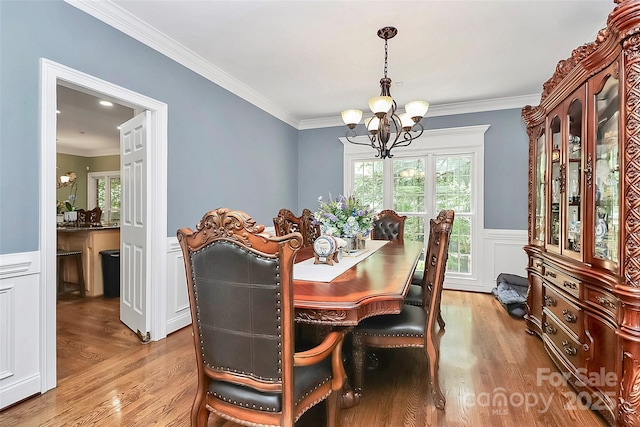 dining area featuring ornamental molding, light hardwood / wood-style flooring, and a notable chandelier