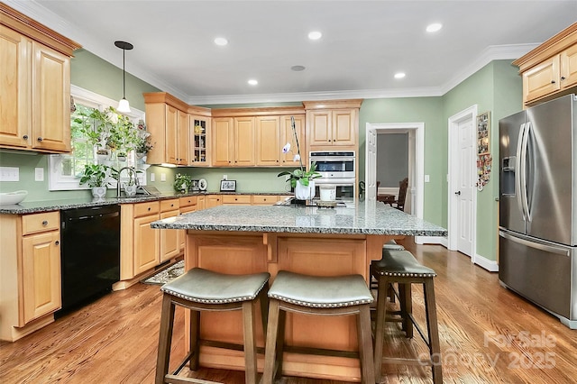 kitchen featuring hanging light fixtures, stainless steel appliances, a kitchen island, dark stone counters, and light wood-type flooring