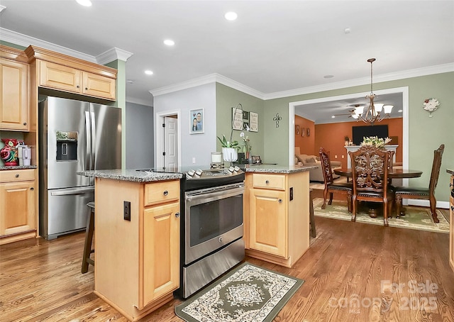 kitchen featuring stainless steel appliances, light stone countertops, a kitchen island, and a chandelier