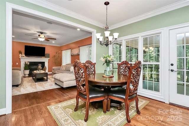 dining space featuring hardwood / wood-style flooring, crown molding, and ceiling fan with notable chandelier