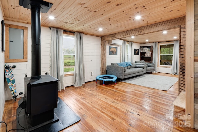 living room featuring a wood stove, a wall mounted air conditioner, wooden ceiling, and light wood-type flooring