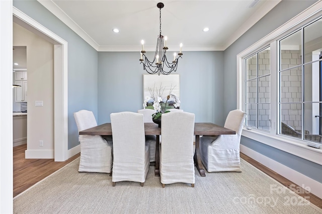 dining space featuring ornamental molding, light wood-type flooring, and an inviting chandelier