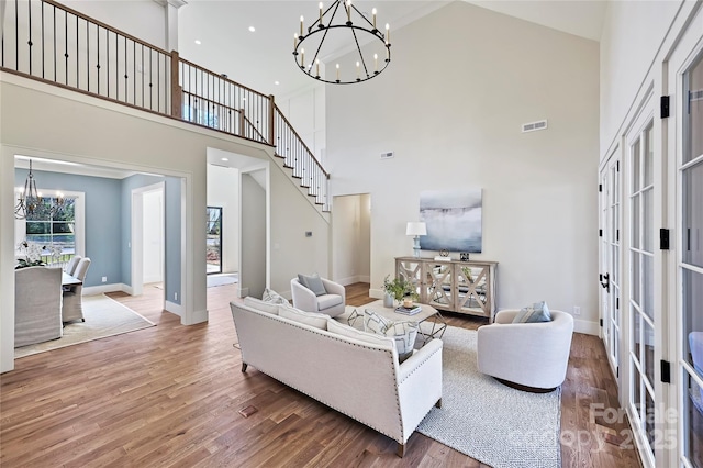 living room with hardwood / wood-style flooring, a chandelier, and a towering ceiling