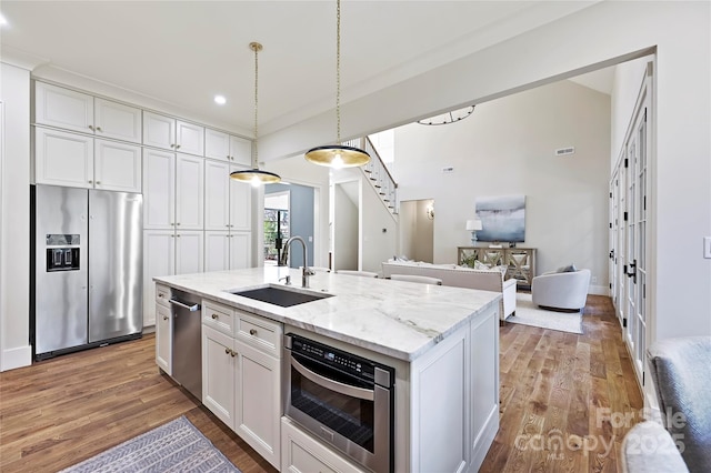 kitchen with white cabinetry, sink, stainless steel appliances, and a center island with sink