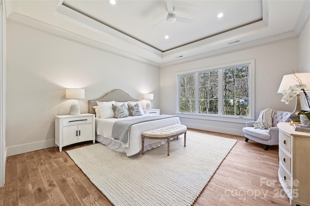 bedroom featuring a raised ceiling, ceiling fan, and light wood-type flooring