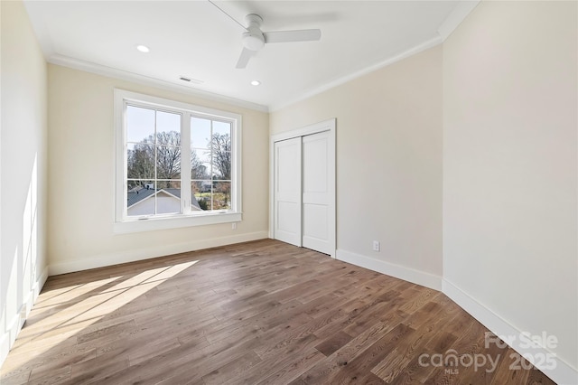 unfurnished bedroom with crown molding, a closet, and hardwood / wood-style flooring