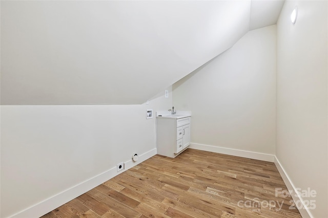 additional living space featuring lofted ceiling, sink, and light hardwood / wood-style floors