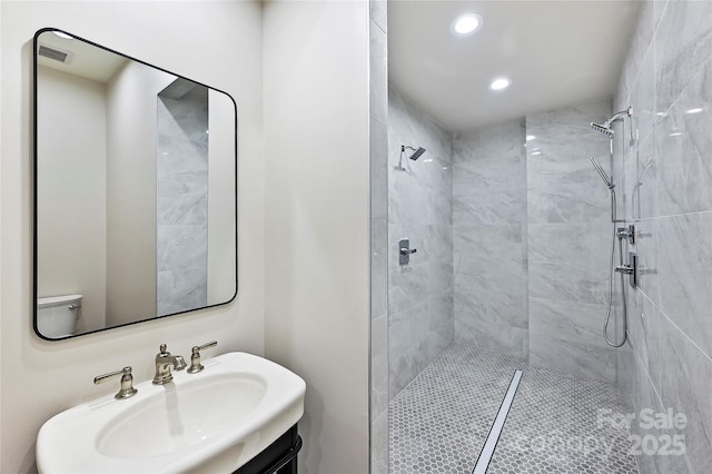 bathroom with tiled shower, vanity, and toilet