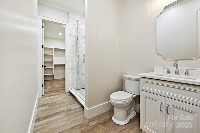 bathroom with vanity, wood-type flooring, a shower with shower door, and toilet