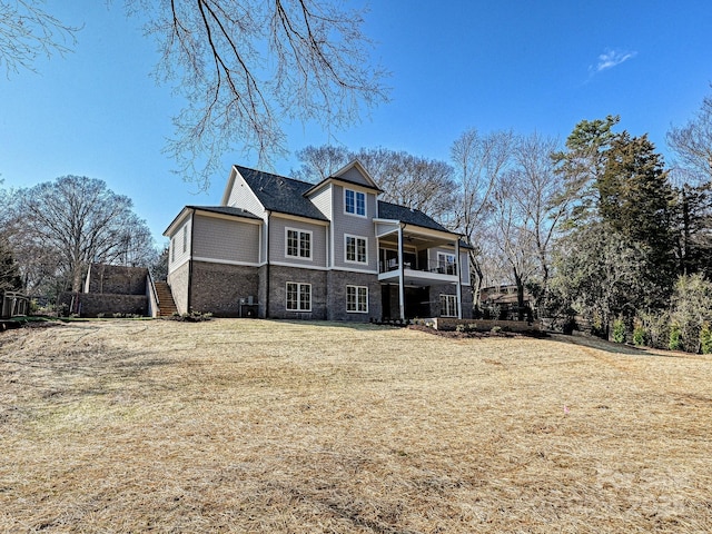 rear view of property with a balcony and a yard