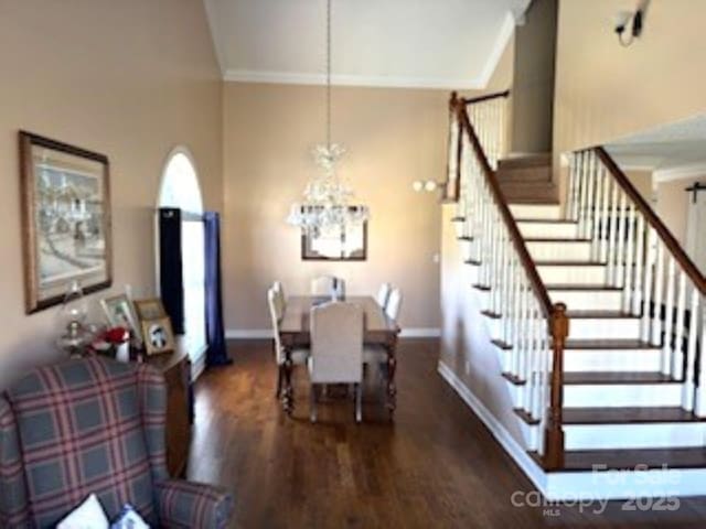 dining space with a notable chandelier, crown molding, dark hardwood / wood-style floors, and a towering ceiling