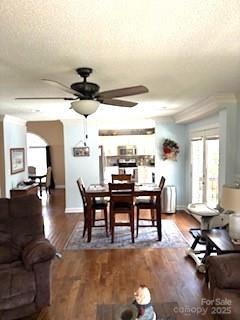 dining area with ceiling fan, wood-type flooring, and a textured ceiling