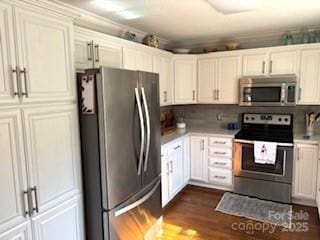 kitchen with stainless steel appliances, dark wood-type flooring, white cabinets, and backsplash