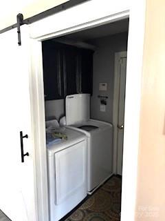 clothes washing area featuring independent washer and dryer, cabinets, and a barn door