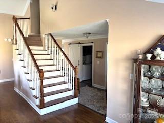 stairs featuring ornamental molding, a barn door, and hardwood / wood-style floors