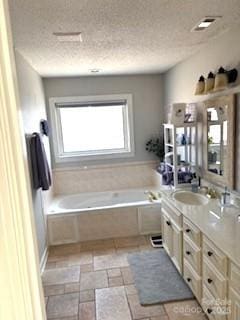 bathroom with vanity, a textured ceiling, and a bathing tub