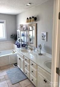 bathroom with tile patterned flooring, vanity, a relaxing tiled tub, and a textured ceiling