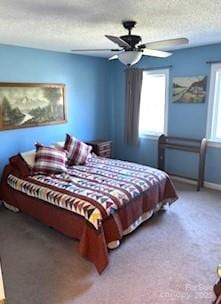 carpeted bedroom featuring ceiling fan and a textured ceiling