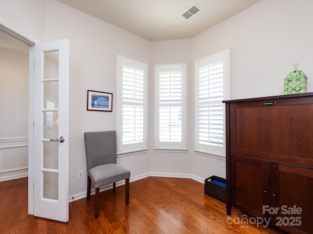 living area featuring visible vents, baseboards, and wood finished floors