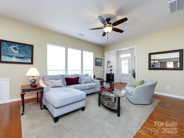 living room with baseboards, visible vents, and wood finished floors