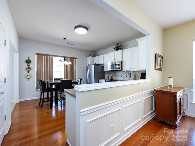 kitchen featuring tasteful backsplash, visible vents, white cabinets, dark wood-style floors, and appliances with stainless steel finishes